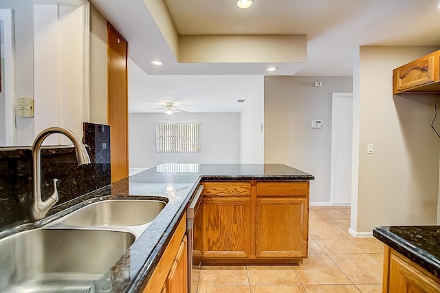 kitchen featuring kitchen peninsula, ceiling fan, sink, light tile floors, and dark stone counters