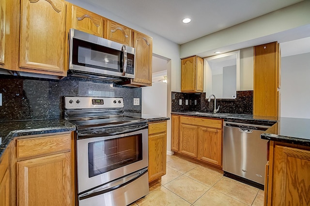 kitchen with sink, light tile floors, dark stone countertops, appliances with stainless steel finishes, and tasteful backsplash