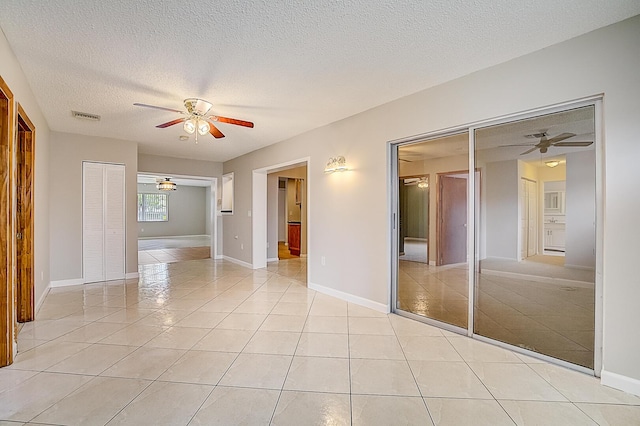 tiled empty room featuring a textured ceiling and ceiling fan