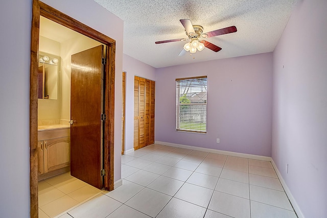 unfurnished bedroom featuring a closet, a textured ceiling, light tile flooring, and ceiling fan