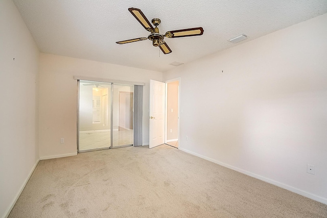 unfurnished bedroom with light carpet, ceiling fan, and a textured ceiling