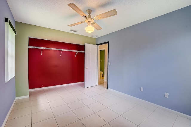 unfurnished bedroom featuring light tile floors, a textured ceiling, a closet, and ceiling fan