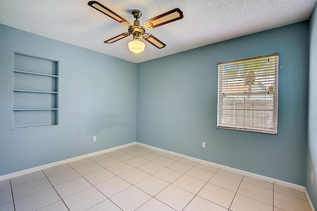 tiled empty room with built in features, ceiling fan, and a textured ceiling