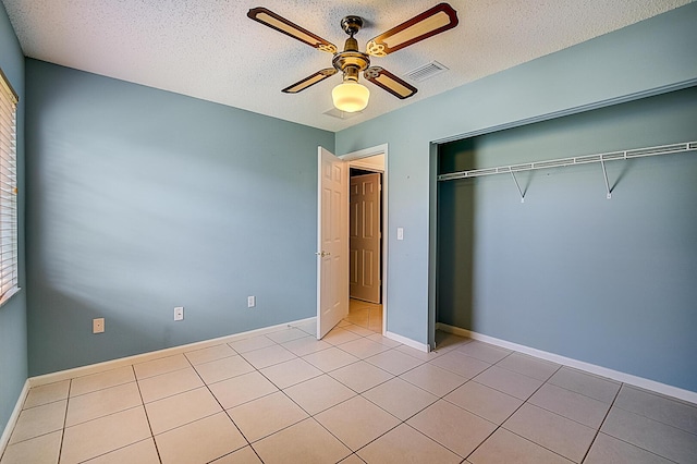 unfurnished bedroom with a closet, a textured ceiling, ceiling fan, and light tile flooring