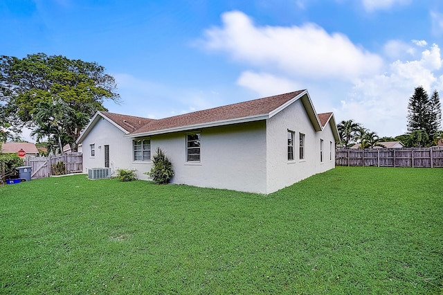 rear view of property with a yard and central air condition unit