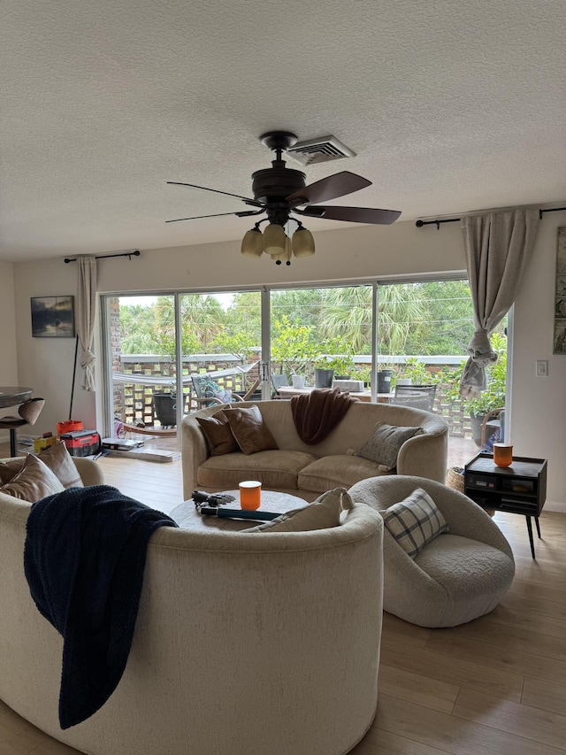 living room featuring wood finished floors, a textured ceiling, and ceiling fan