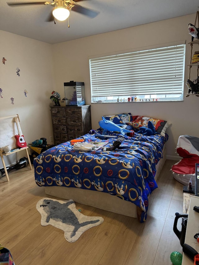 bedroom featuring wood finished floors, multiple windows, and a ceiling fan