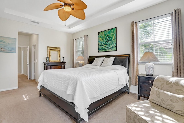 carpeted bedroom featuring a raised ceiling and ceiling fan