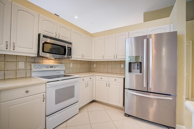 kitchen with appliances with stainless steel finishes, white cabinetry, tasteful backsplash, and light tile flooring