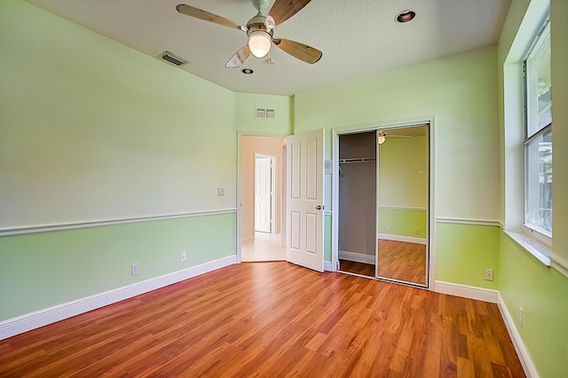 unfurnished bedroom with a closet, light hardwood / wood-style floors, and ceiling fan