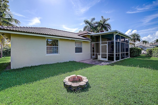 back of property featuring an outdoor fire pit, a sunroom, and a yard