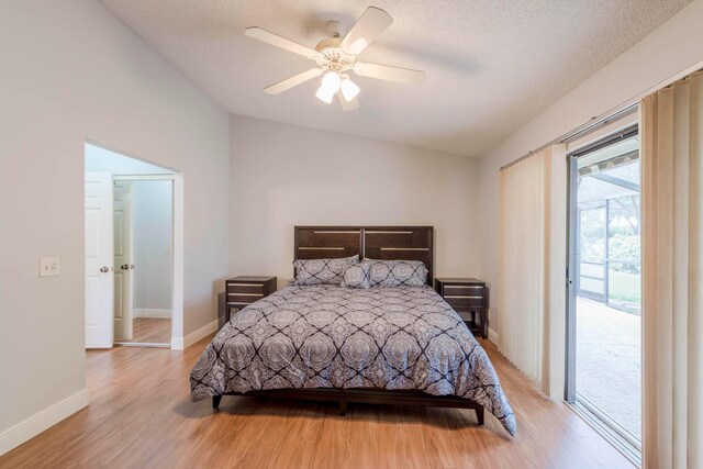 bedroom featuring light hardwood / wood-style floors, access to exterior, vaulted ceiling, ceiling fan, and a textured ceiling