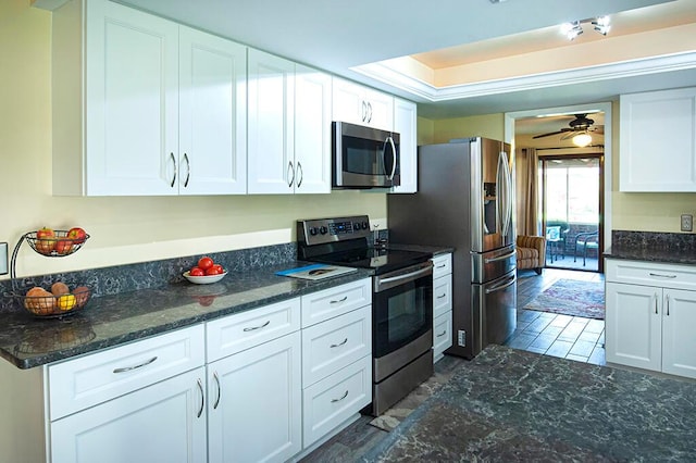 kitchen featuring dark stone countertops, appliances with stainless steel finishes, white cabinetry, and ceiling fan