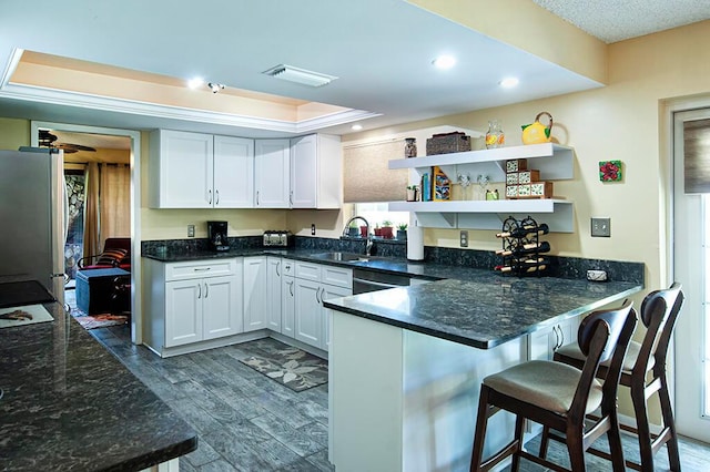 kitchen featuring kitchen peninsula, dark hardwood / wood-style flooring, white cabinets, and sink