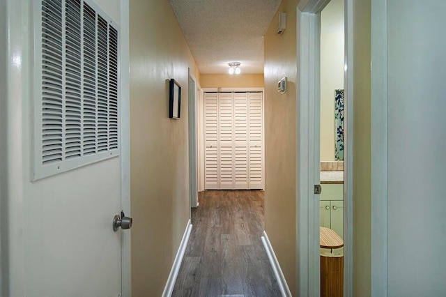 hall with a textured ceiling and dark hardwood / wood-style flooring