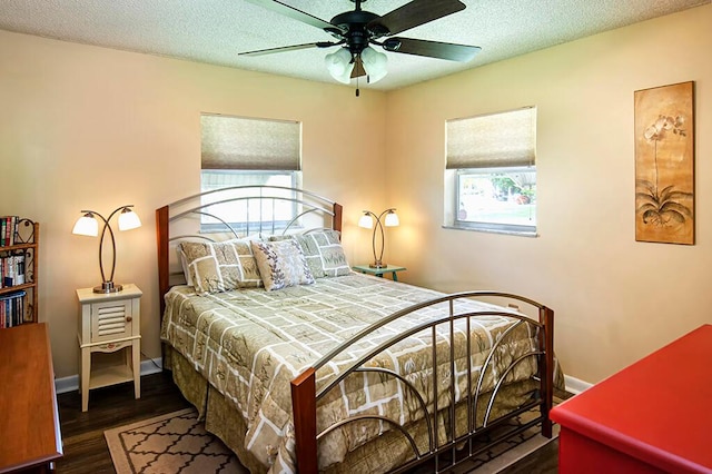 bedroom with ceiling fan, a textured ceiling, and dark wood-type flooring