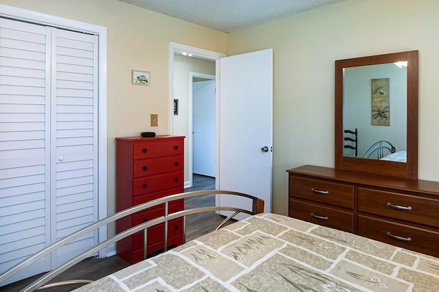 bedroom with a closet, a textured ceiling, and dark hardwood / wood-style flooring