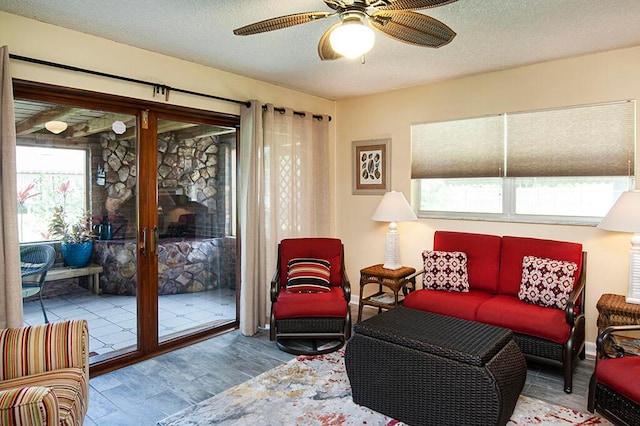 living room with a textured ceiling, ceiling fan, and light wood-type flooring