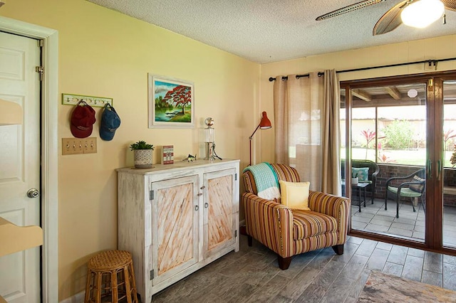 living area with ceiling fan, a textured ceiling, and dark hardwood / wood-style flooring