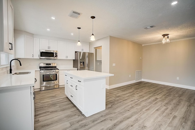 kitchen featuring a center island, stainless steel appliances, white cabinets, and light hardwood / wood-style flooring