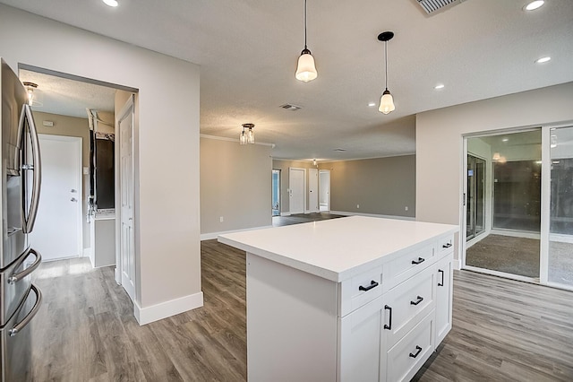 kitchen with decorative light fixtures, stainless steel fridge, white cabinets, light carpet, and a center island