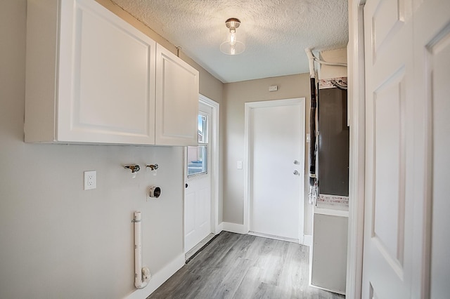 clothes washing area featuring cabinets, a textured ceiling, and wood-type flooring