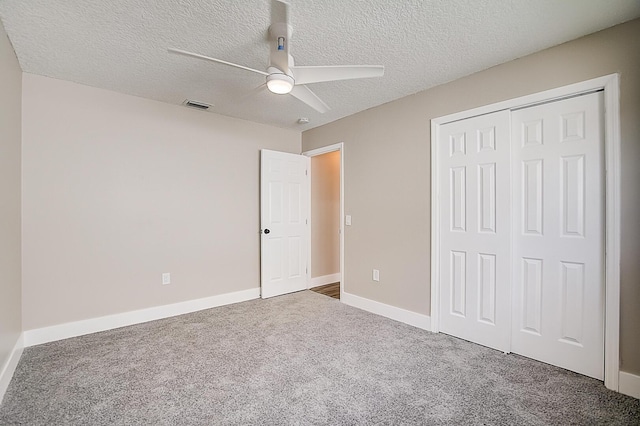 unfurnished bedroom featuring a textured ceiling, a closet, ceiling fan, and dark colored carpet