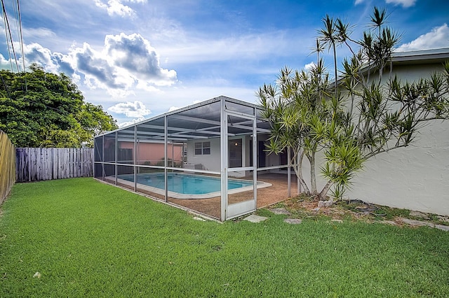 view of swimming pool featuring a lawn, a patio area, and a lanai