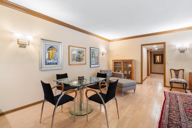 dining area with crown molding, light hardwood / wood-style flooring, and a textured ceiling