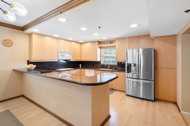 kitchen with white appliances, kitchen peninsula, and light wood-type flooring