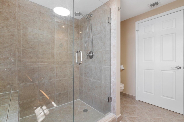 bathroom featuring a shower with door, tile floors, and toilet