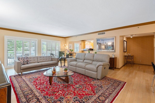 living room featuring light hardwood / wood-style flooring, crown molding, and a textured ceiling