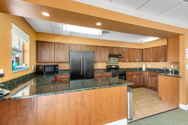 kitchen with black appliances, kitchen peninsula, light tile floors, dark stone counters, and fume extractor