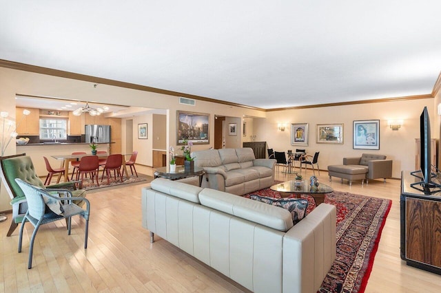 living room featuring crown molding, light hardwood / wood-style floors, and sink