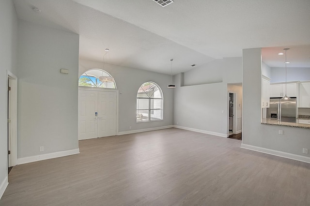 unfurnished living room featuring high vaulted ceiling and light hardwood / wood-style flooring