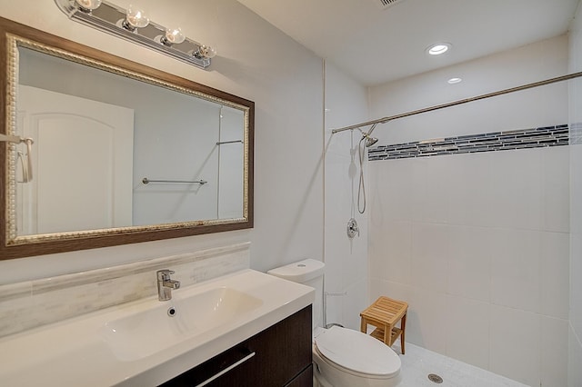 bathroom featuring large vanity, toilet, and tiled shower