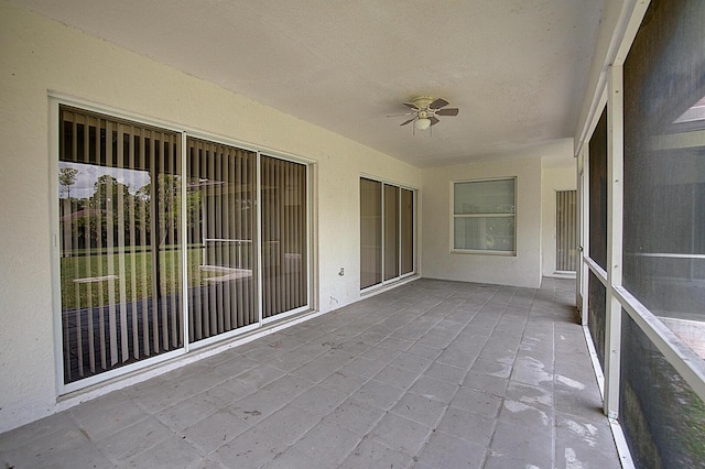 unfurnished sunroom featuring ceiling fan