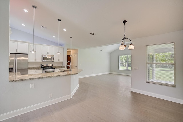 kitchen with hanging light fixtures, white cabinets, appliances with stainless steel finishes, and lofted ceiling