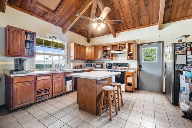 kitchen featuring ceiling fan, appliances with stainless steel finishes, beam ceiling, wooden ceiling, and a kitchen island