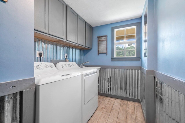 laundry area featuring washing machine and clothes dryer, cabinets, hookup for an electric dryer, and light hardwood / wood-style flooring