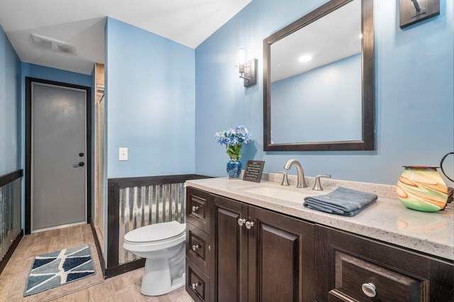 bathroom featuring toilet, vanity, and hardwood / wood-style floors