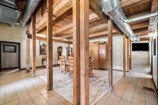 interior space featuring brick wall, light tile floors, and wood ceiling