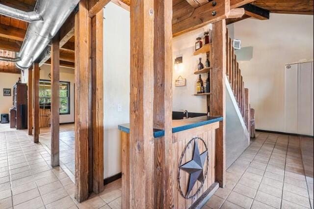 interior space with light tile flooring and vaulted ceiling with beams