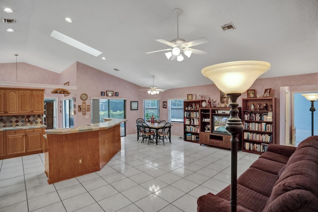 kitchen featuring a skylight, backsplash, ceiling fan, light tile flooring, and a center island