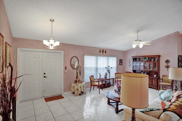 tiled entryway with a textured ceiling, ceiling fan with notable chandelier, and vaulted ceiling