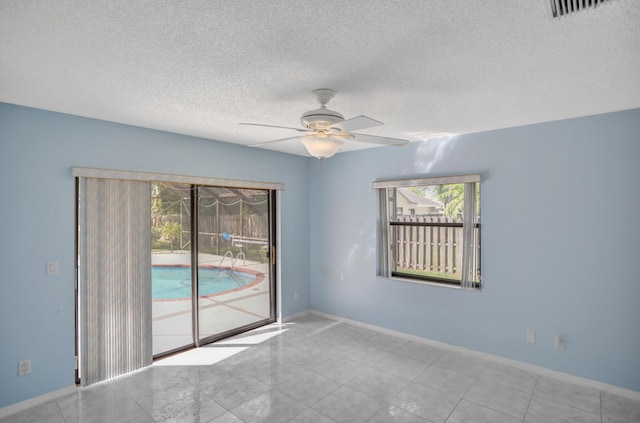 tiled spare room featuring a textured ceiling and ceiling fan