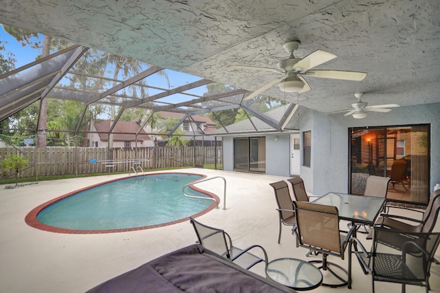 view of swimming pool featuring glass enclosure, ceiling fan, and a patio area