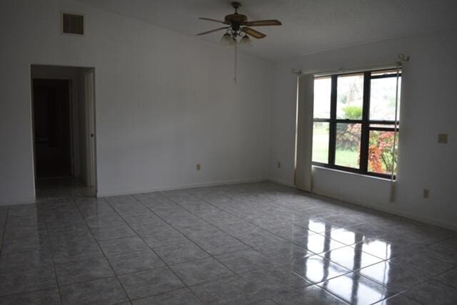 spare room with a healthy amount of sunlight, tile floors, ceiling fan, and lofted ceiling