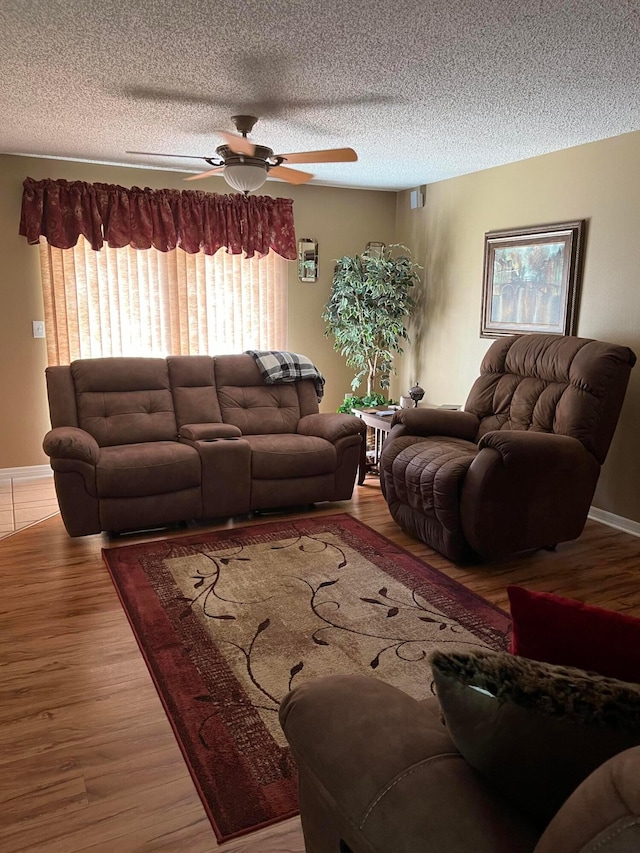 living room featuring a textured ceiling, ceiling fan, and light wood-type flooring