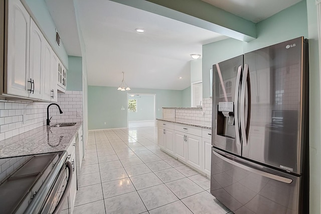 kitchen with tasteful backsplash, white cabinets, appliances with stainless steel finishes, and light stone countertops